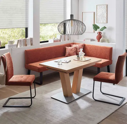 Esszimmer mit Eckbank und Stühlen in Terracotta, Holz-Esstisch mit Metallfuß und stilvoller Hängelampe – moderne Eckbankgruppe, platzsparende Sitzlösung, gemütliches Ambiente mit warmen Farbtönen.